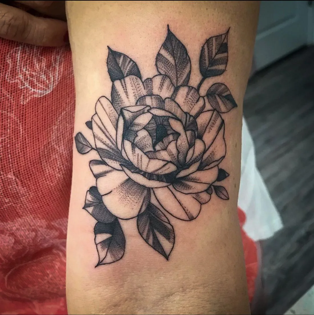 Tatuaje whipshading: flor grande con hojas, en el brazo