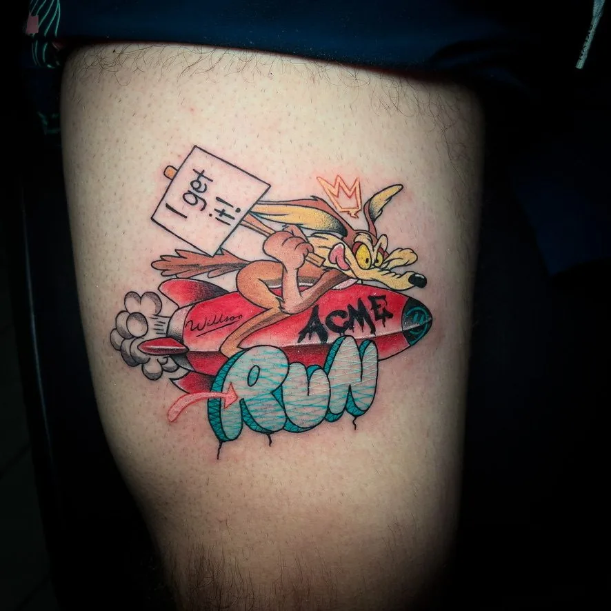 Tatuaje estilo parche bordado: personaje de caricatura sobre un cohete con letras «RUN», en la pierna